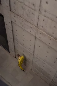 man in yellow track jacket and pants walking along the grey concrete wall